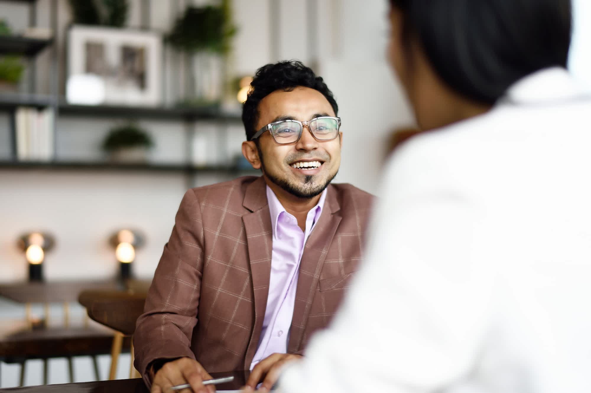 A man in a suit smiles during a business meeting.